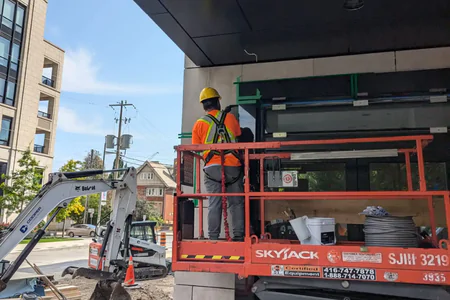 NHC Restoration crew caulking window frames from a scissor lift